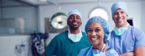 Portrait Of Multi-Cultural Surgical Team Standing In Hospital Operating Theater